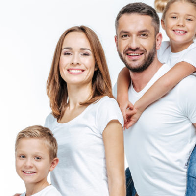 Happy family in white t-shirts and jeans standing together and looking at camera isolated on white